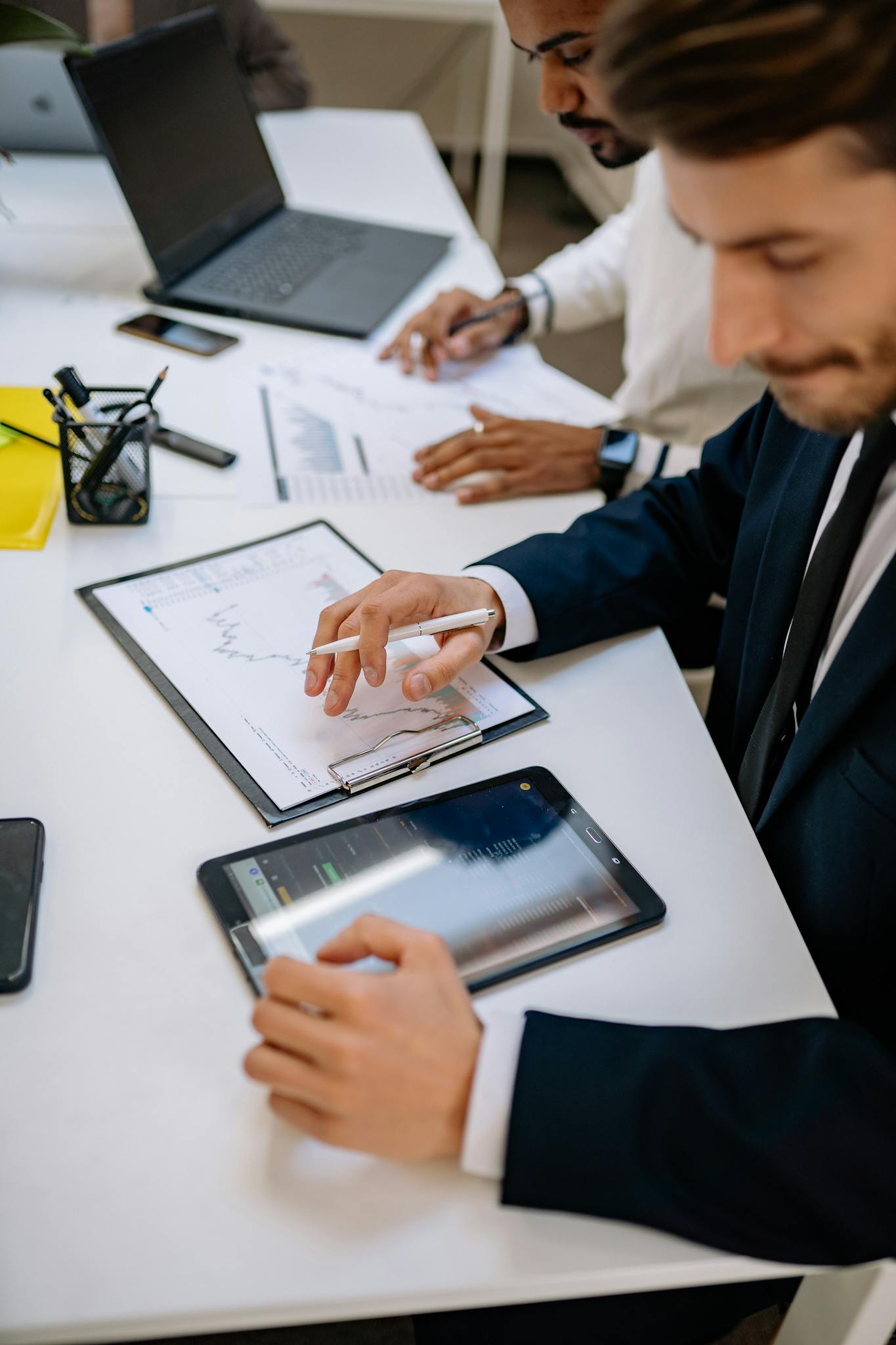 Business professionals working with tablet and documents in a modern office.